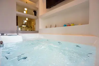 a bath tub filled with blue water in a bathroom at East Seafront Suite in Chania Town