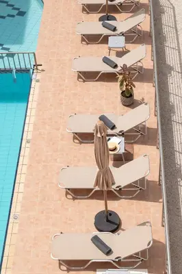 an overhead view of a row of lounge chairs next to a pool at Thelèsi Apartments, 100m from the beach in Stalos