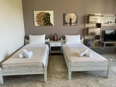 two beds in a room with a desk and a tv at Kyparissos Apartment I in Kissamos