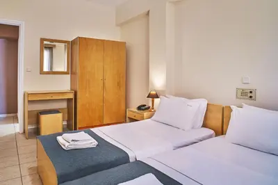 a hotel room with two beds and a desk at Veronica Hotel in Kato Daratso