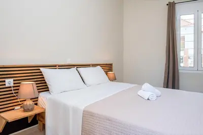 a bedroom with a bed with white sheets and a window at Elegant Apartment in Chania Town