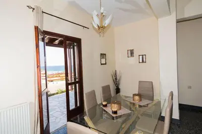 a dining room with a glass table and a view of the ocean at Stalos View in Stalos