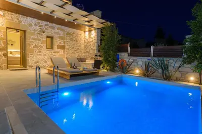 a swimming pool in a backyard at night at Effrosini Traditional Home in Nopíyia