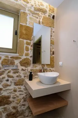 a bathroom with a white bowl sink and a stone wall at Effrosini Traditional Home in Nopíyia
