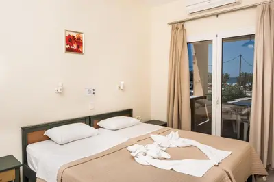 a bedroom with a bed with towels on it at Mythos Beach Hotel Apartments in Maleme