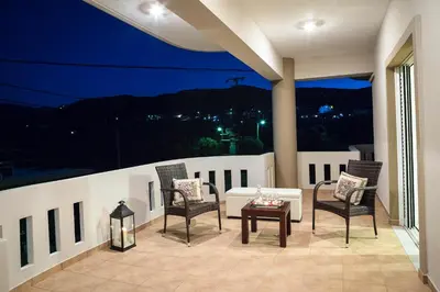 a patio with chairs and a couch on a balcony at night at Joanna 's Loft in Kissamos