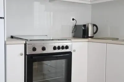 a stove top oven in a kitchen with white cabinets at Villa Elea Apartments in Spiliá