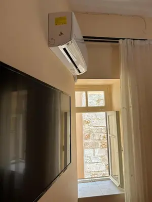 a living room with a television and a window at Sofias Home in Chania Town