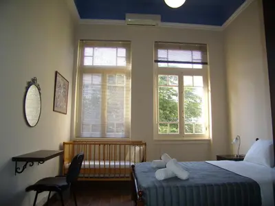 a bedroom with a bed and a chair and two windows at Neoclassical Glamour in Chania Town