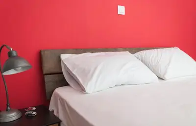 a bed with white pillows and a red wall at Veranda Apartment in Chania Town