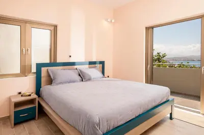 a bedroom with a large bed and a large window at Blue Sea Chania Villa in Chania Town
