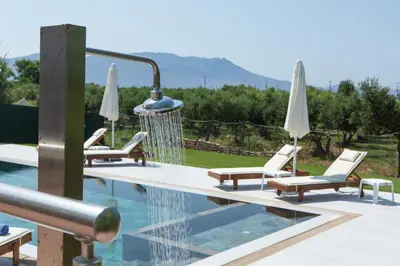 a swimming pool with lounge chairs and umbrellas at Nikis Apartments Kisamos in Drapaniás