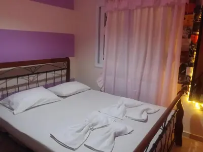 a bedroom with a bed with white sheets and a window at Kostaspant apartment in Gerani Chanion