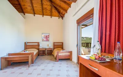 a bedroom with two beds and a kitchen with a table at ERIA RESORT for people with special abilities in Maleme