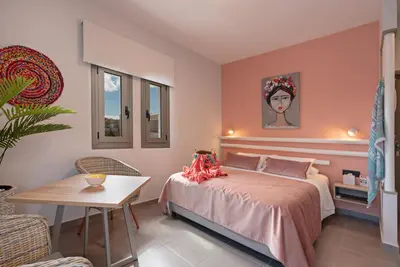 a bedroom with a bed and a table and a chair at Sonio Beach - Que Bella Collection in Plataniás