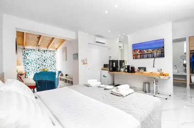 a white bedroom with a large white bed and a tv at Notus Chania Crete in Chania Town