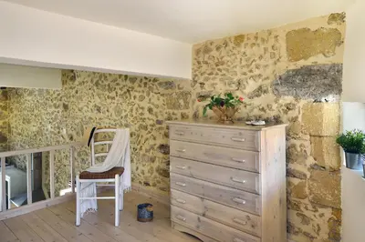a dresser and a chair in a room with stone walls at Mousa Thalia in Kissamos