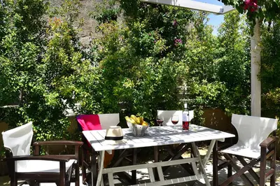 a white table and chairs on a patio with trees at Mousa Thalia in Kissamos