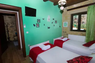 a bedroom with two beds and a tv on the wall at Mansion Rokka in Kissamos