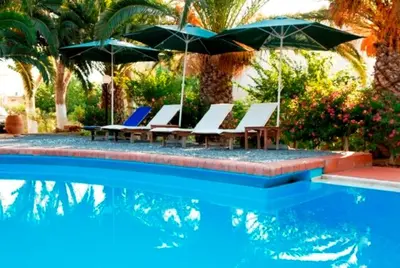 a group of chairs and umbrellas next to a pool at Kalives Apartments in Kalyves