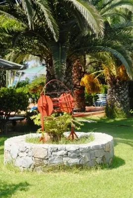 a statue in the grass in front of a palm tree at Kalives Apartments in Kalyves