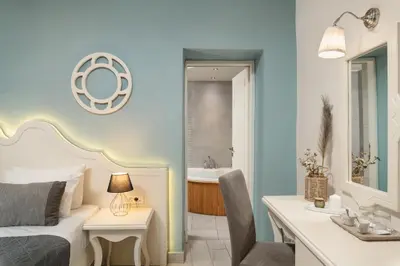 a bedroom with a bed and a bathroom with a sink at Elia Palazzo Hotel in Chania Town