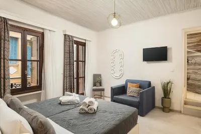 a bedroom with a bed and a chair and a tv at Elia Palazzo Hotel in Chania Town