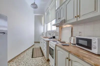 a large kitchen with white cabinets and a microwave at Samouil Apartment steps from the beach in Chania Town