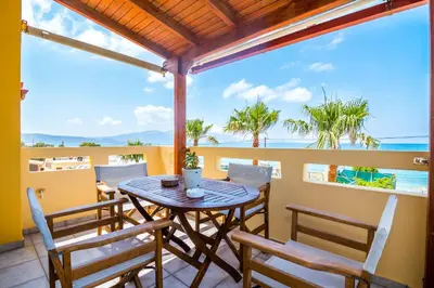a table and chairs on a balcony with a view of the ocean at Thalassa Apartments in Kissamos