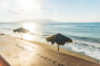 a beach with two umbrellas and the ocean at Thalassa Apartments in Kissamos