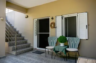 two chairs and a table with a plant on a porch at Cottage home at South Chania in Grigorianá