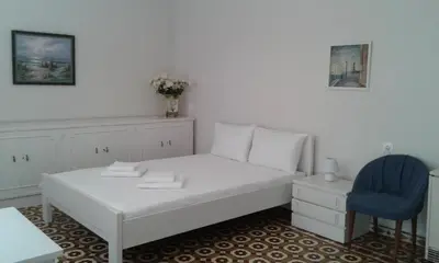 a bedroom with a white bed and a blue chair at White Rose in Chania Town