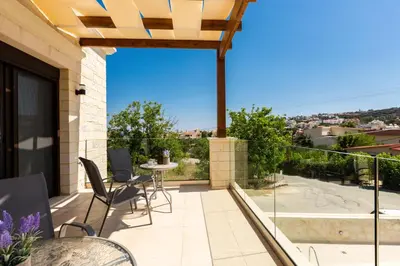 a patio with a table and chairs on a balcony at Eudora Luxury Stone Villa in Almirida