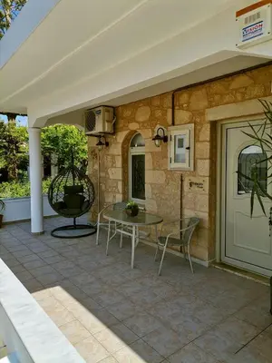a patio with a table and chairs next to a stone wall at Harmony House in Kissamos