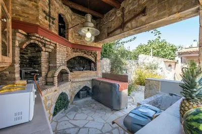 an outdoor patio with a stone fireplace and a grill at Niko's art Villa in Chania in Perivólia