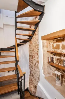 a wooden staircase in a room with a stone wall at Casa Emily in Chania Town