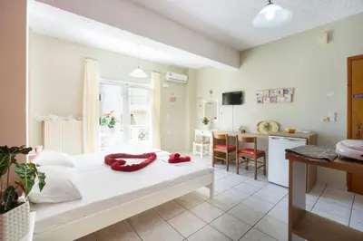 a bedroom with a large white bed and a kitchen at Steps From The Beach Aprt in Chania Town