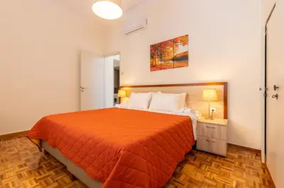 a bedroom with a bed with an orange bedspread at Evridiki's House Central Chania in Chania Town