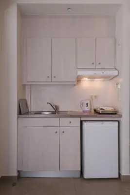 a kitchen with white cabinets and a sink and a refrigerator at Poseidon Studios & Apartments in Palaiochóra