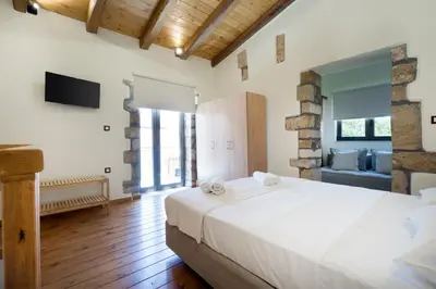 a bedroom with a large white bed and a tv at Kyriaki's Traditional House in Galatás