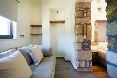 a living room with a couch and a stone wall at Kyriaki's Traditional House in Galatás