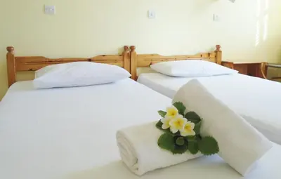 two beds with white sheets and a flower on them at Katerina Palaiochora in Palaiochóra