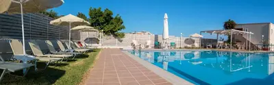 a swimming pool with chairs and umbrellas next to a building at Dimitra & Evdokia Hotel in Agia Marina Nea Kydonias