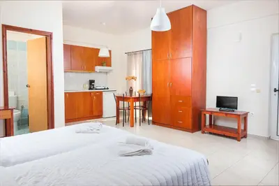 a bedroom with a white bed and a kitchen at Dimitra & Evdokia Hotel in Agia Marina Nea Kydonias