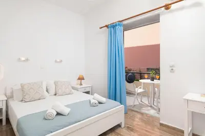 a bedroom with a bed with a blue curtain at Dimitra & Evdokia Hotel in Agia Marina Nea Kydonias
