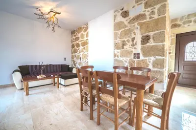 a dining room with a table and chairs and a stone wall at Estia in Plátanos