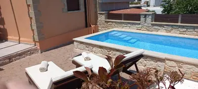 a swimming pool with two white lounge chairs next to it at Estia in Plátanos