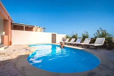 a swimming pool with lounge chairs on a patio at Nemesis in Plátanos