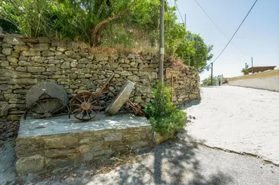 a stone wall with an old cart sitting next to a street at Dream House in Perivólia