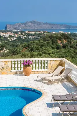 a patio with chairs and a swimming pool on a balcony at Villa Ariadne in Stalos